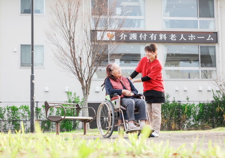 庭で散歩するスタッフと入居者